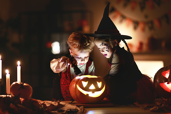 魔女の仮想をしてかぼちゃを見つめる子供たちの写真