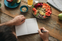 サラダを食べながらノートを書く女性の写真