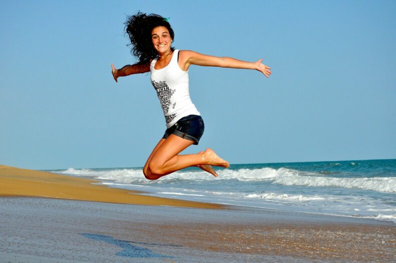 ビーチで飛び跳ねる女性の写真