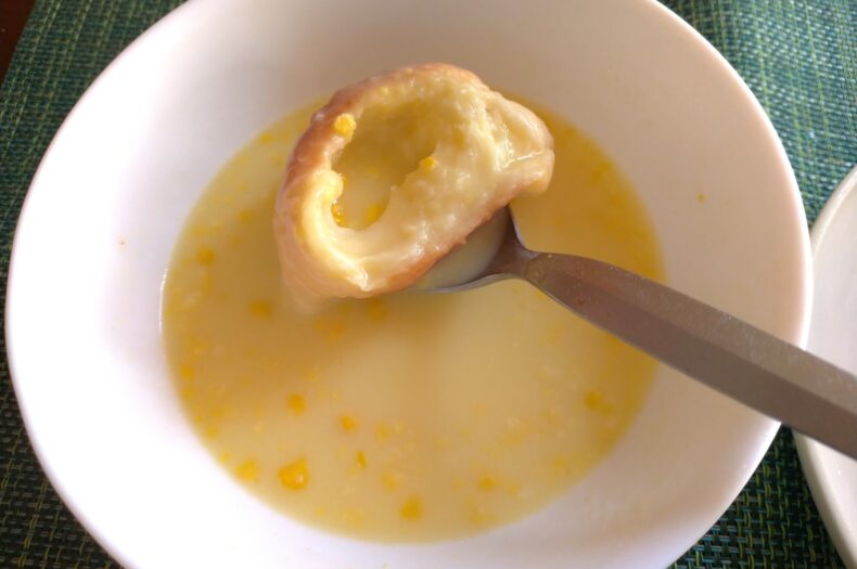 塩バターパンをコーンスープに浸している写真